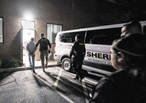 Sheriff officers escort an individual from their building in Foothill Farms at night.