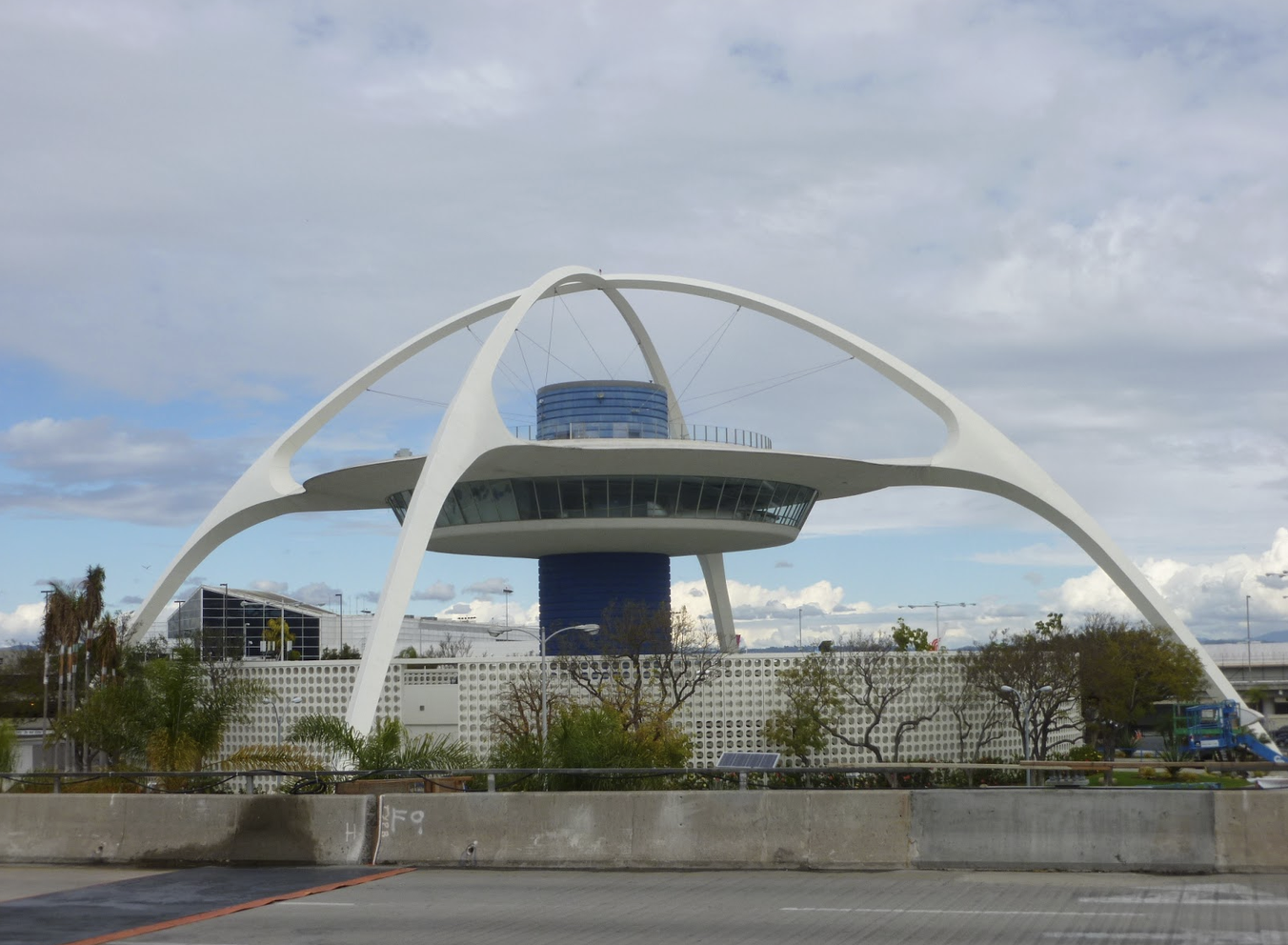 The image features a futuristic architectural structure, likely a terminal or observation building, with a distinctive white canopy.