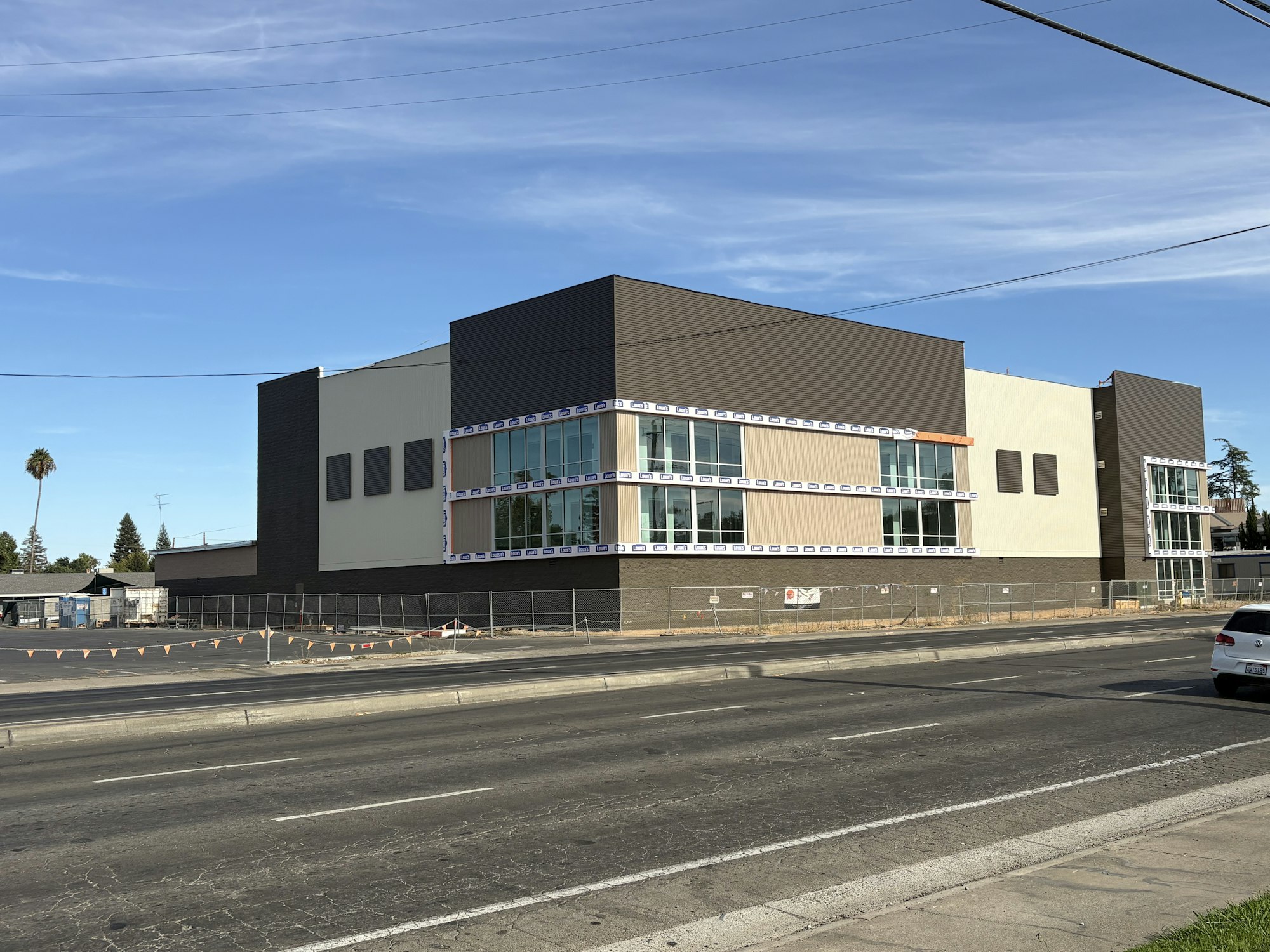 A large, modern building under construction, featuring large windows and a mix of brown and beige exterior.