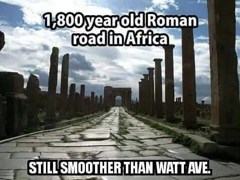 An ancient Roman road in Africa, with a humorous comparison suggesting it's smoother than a modern street.