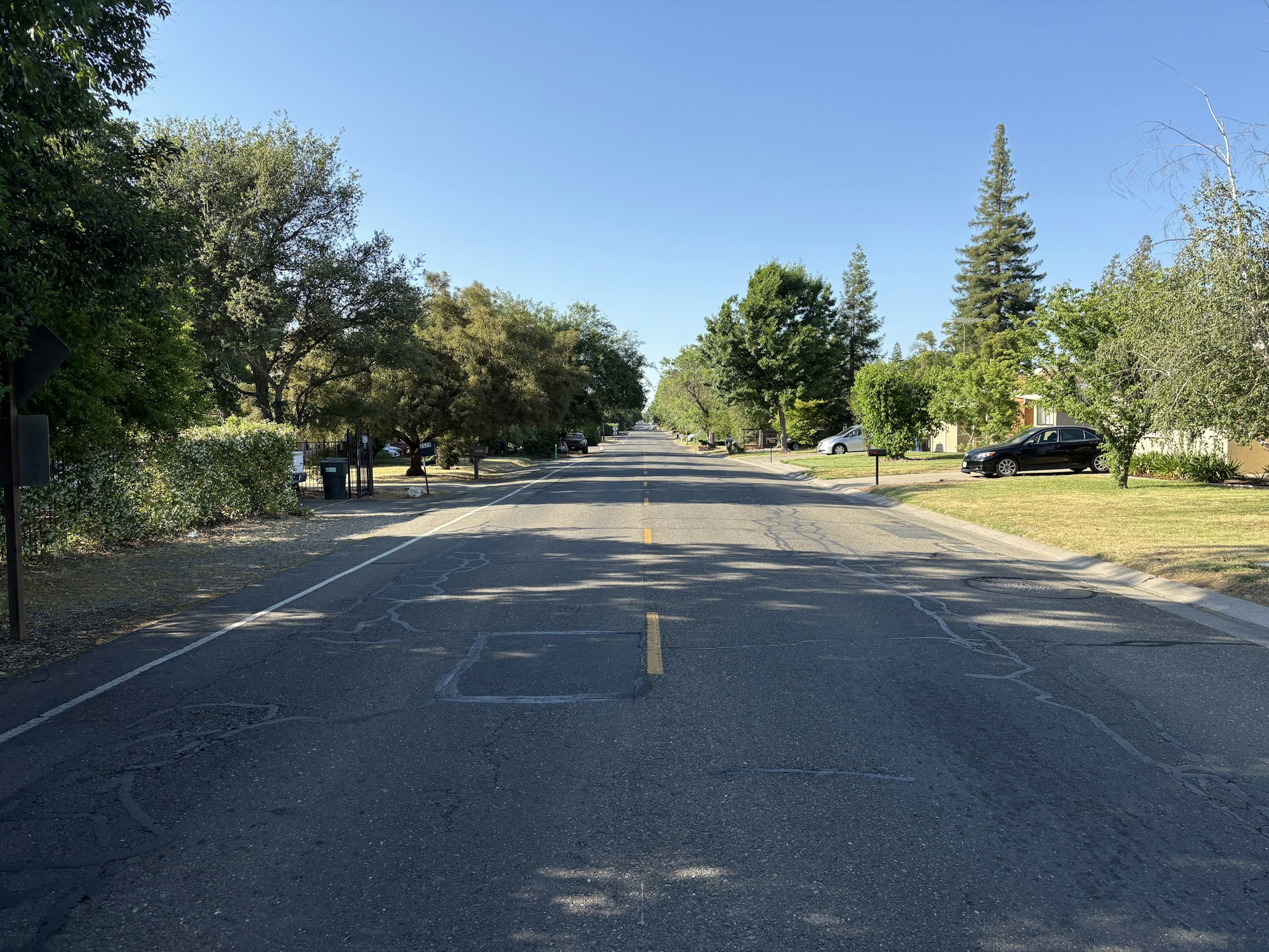 MIssion Avenue, a suburban street with trees lining both sides, parked cars, and a clear blue sky above. It divides Arden Arcvade and Carmichael