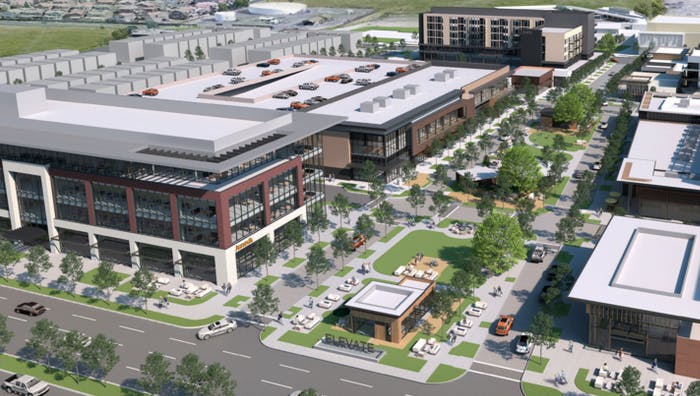 Aerial view of a modern mixed-use development featuring buildings, parking spaces, green areas, and pathways.
