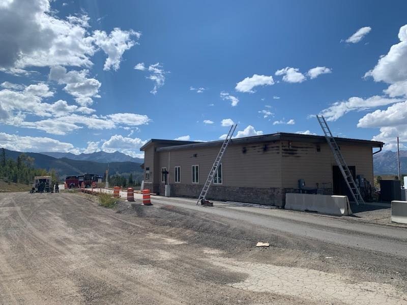 Construction site with a half-finished building, ladders, clear sky, and distant mountains.