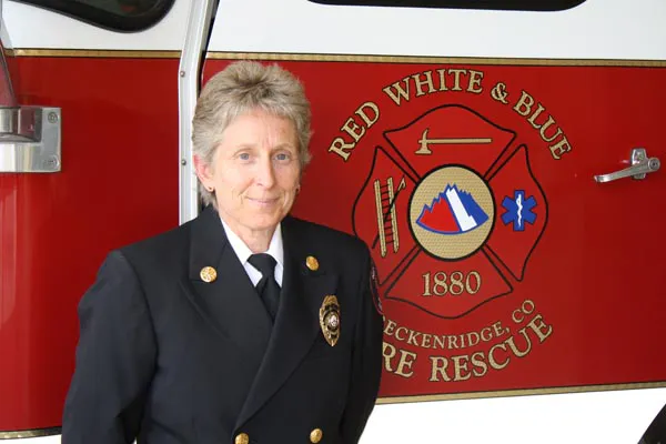 A person in a fire department uniform stands next to a red fire vehicle, featuring the "Red White & Blue Fire Rescue" logo.