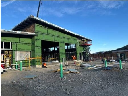 Construction site with a partially completed building, scaffolding, and various construction materials.