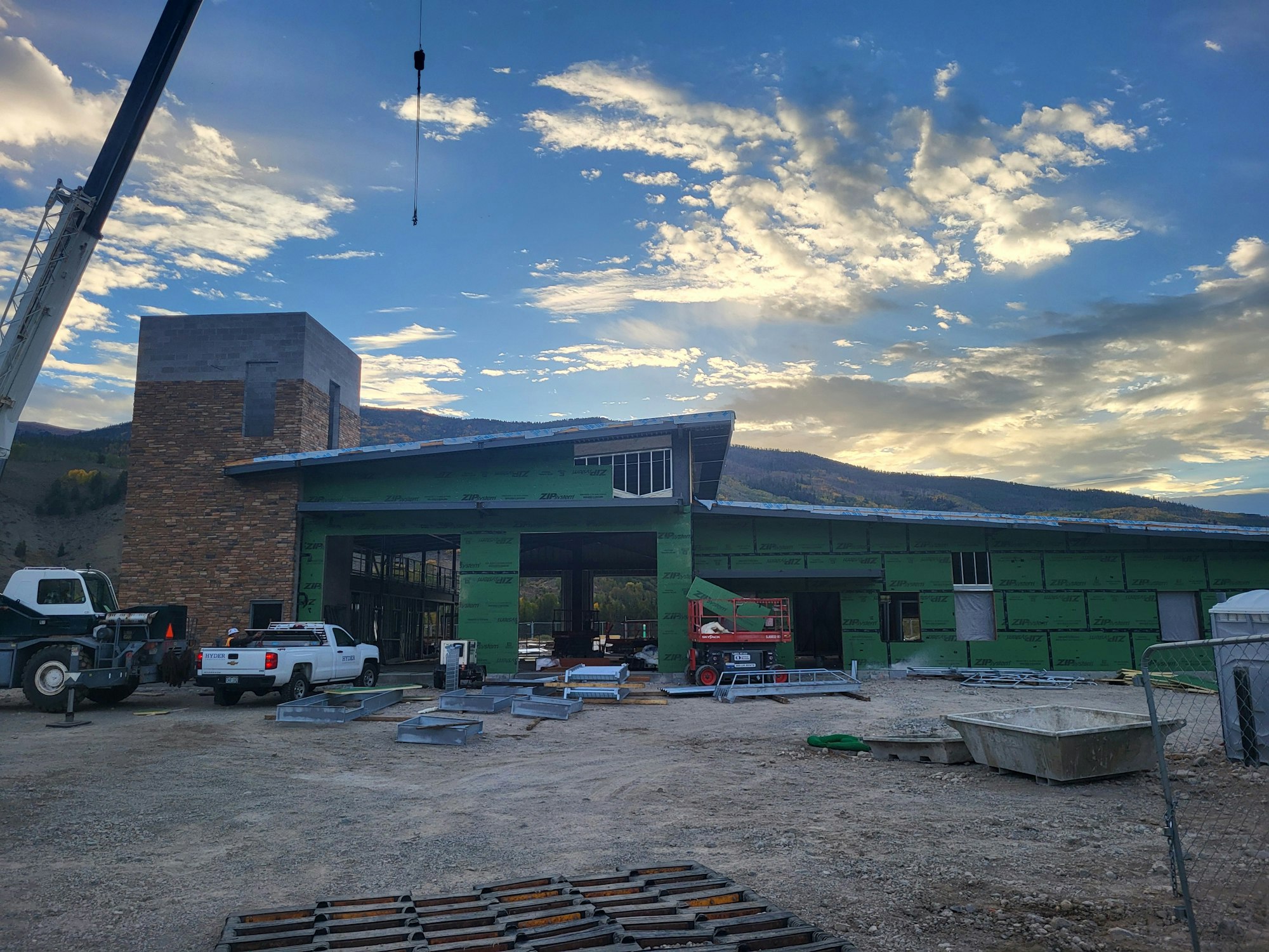 Construction site with building under progress, crane, and a scenic dusk sky.