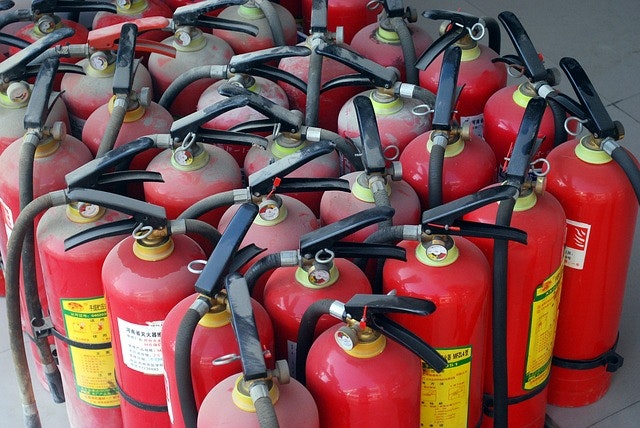 A collection of red fire extinguishers with hoses and nozzles.