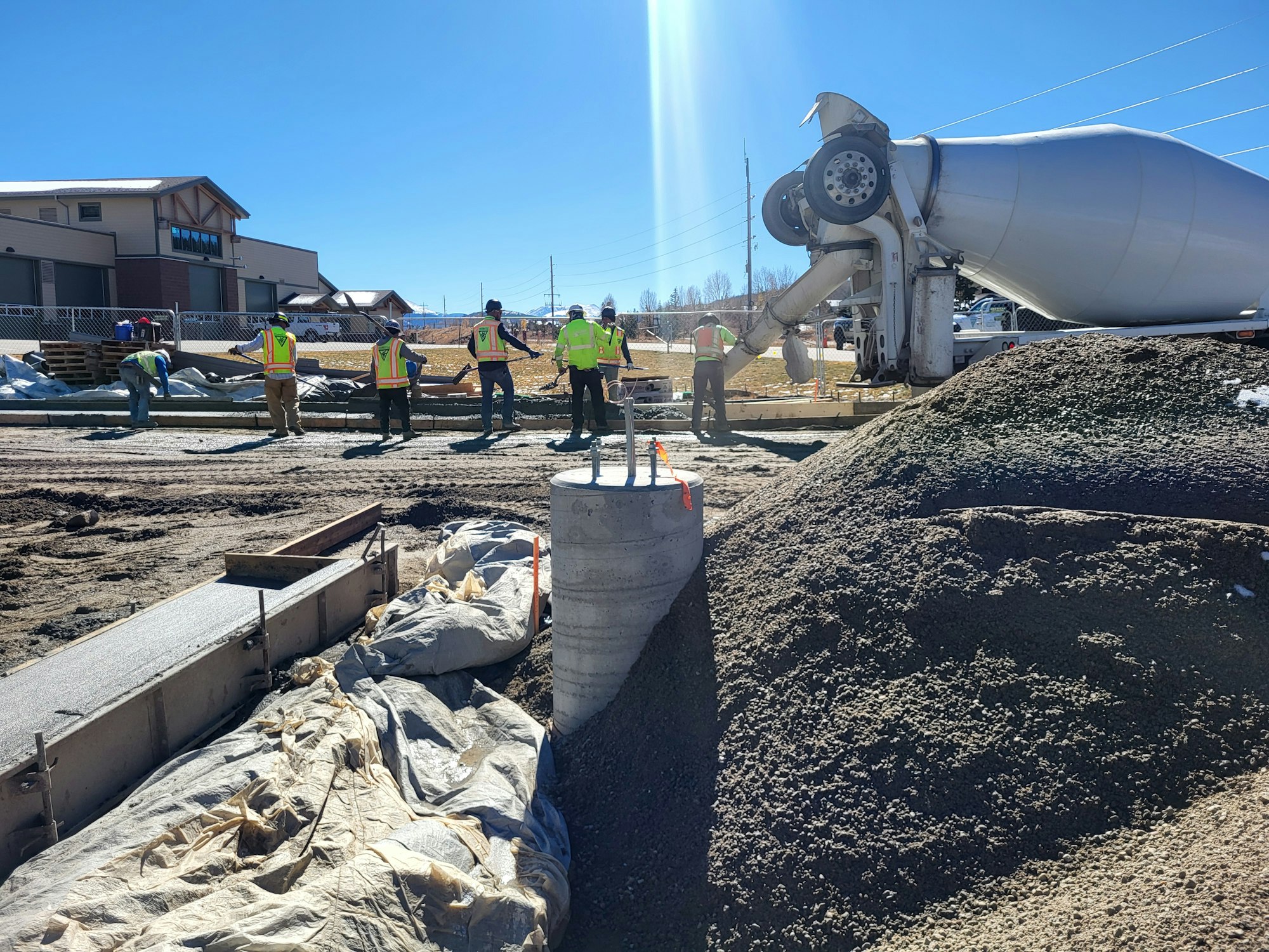 Construction workers pouring concrete from a cement mixer truck at a building site.