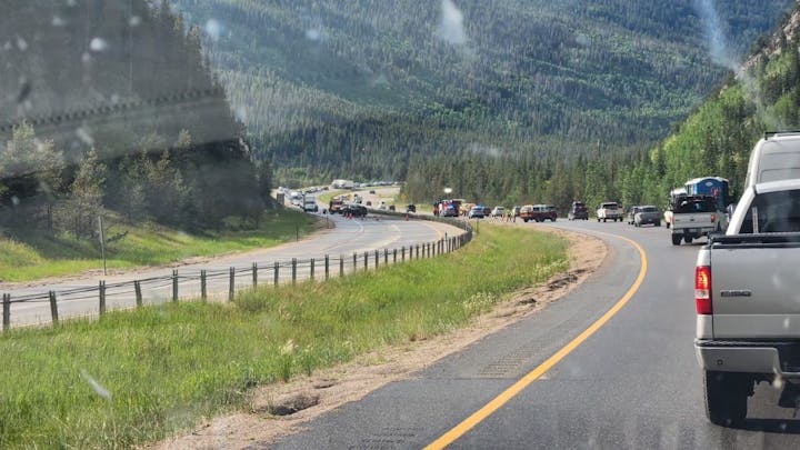 Traffic on a mountain road with cars lining up, surrounded by trees and hills.