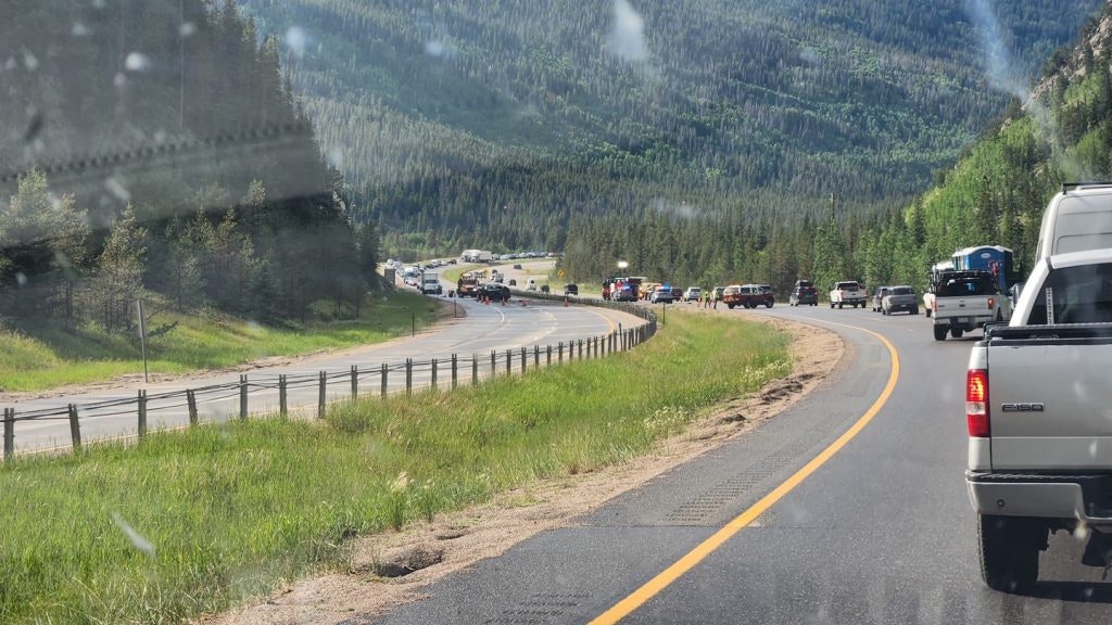 Traffic on a mountain road with cars lining up, surrounded by trees and hills.