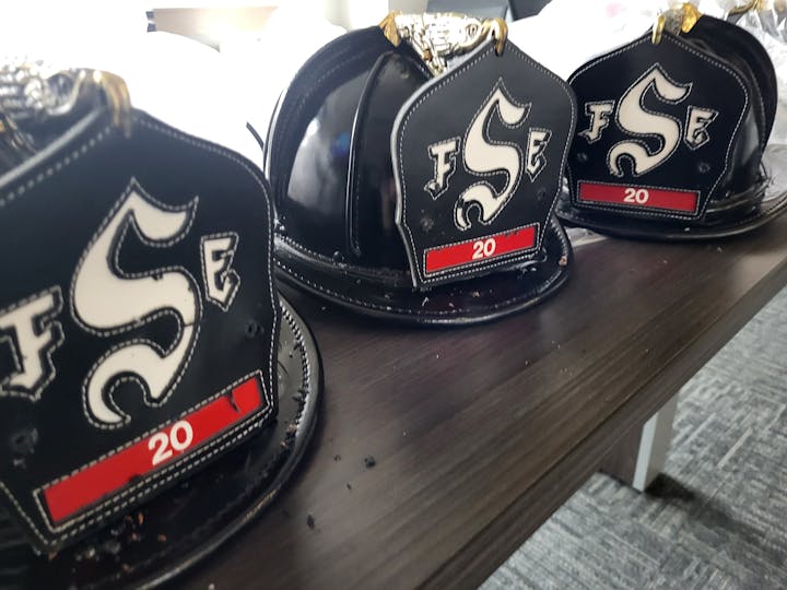 Three traditional firefighter helmets commemorating 20 years of service to Summit Fire & EMS and its predecessor organizations.