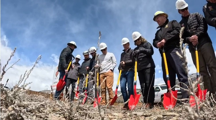 Group of people with hardhats and shovels at a groundbreaking ceremony.