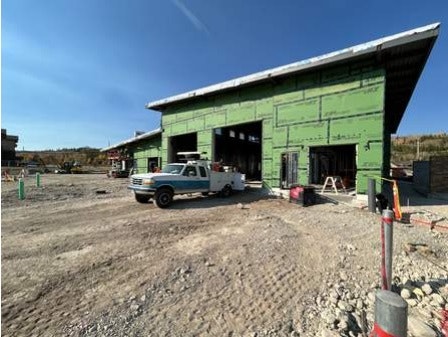 A construction site with a green building under construction and a white truck parked outside.