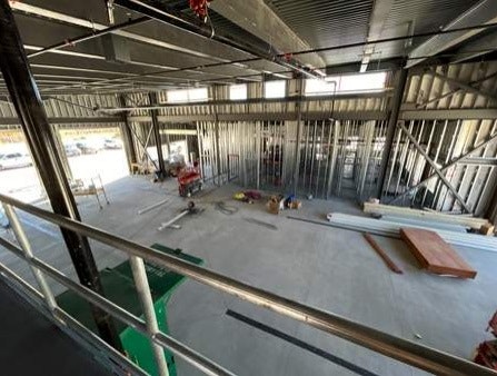 Interior construction site with metal framing, tools on the floor, and exposed ductwork.