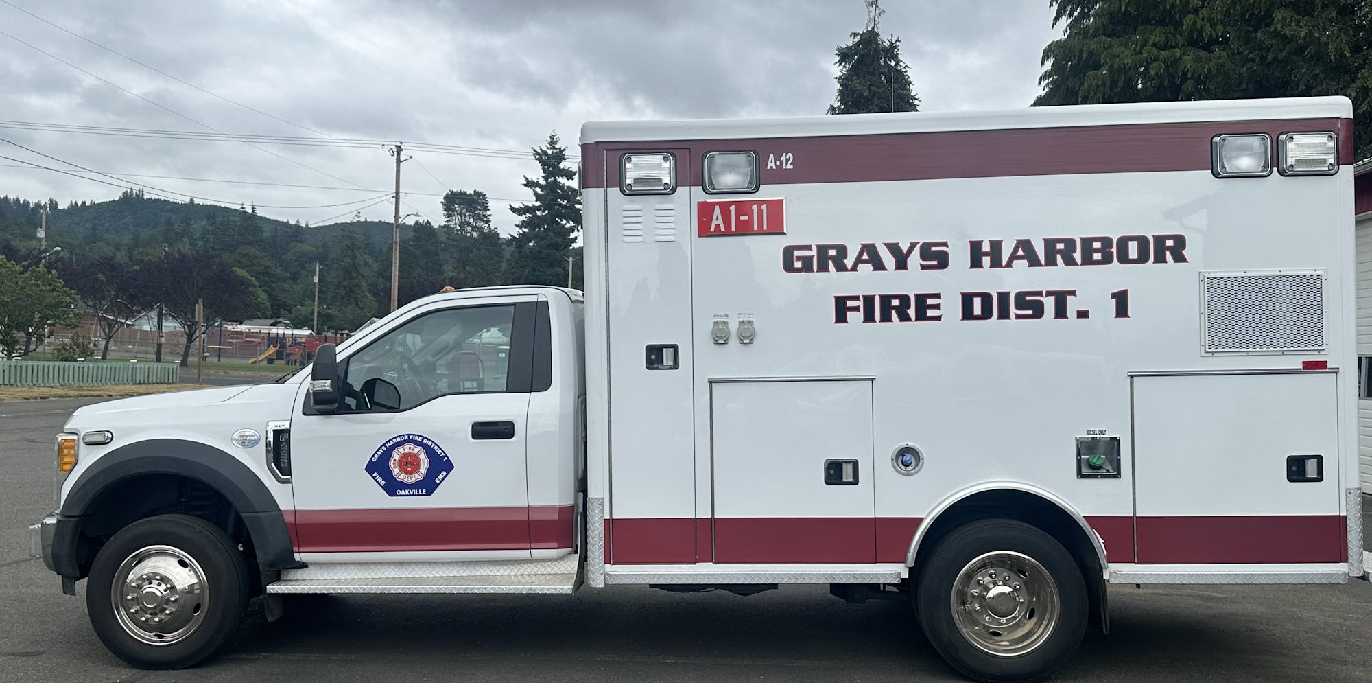 Ambulance labeled "Grays Harbor Fire Dist. 1" parked on a street, cloudy sky above.