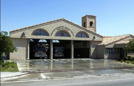 A fire station with two fire trucks visible inside the open garage bays.