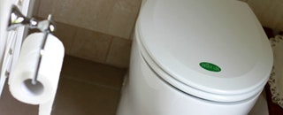 A toilet with a closed lid and a roll of toilet paper on a holder.