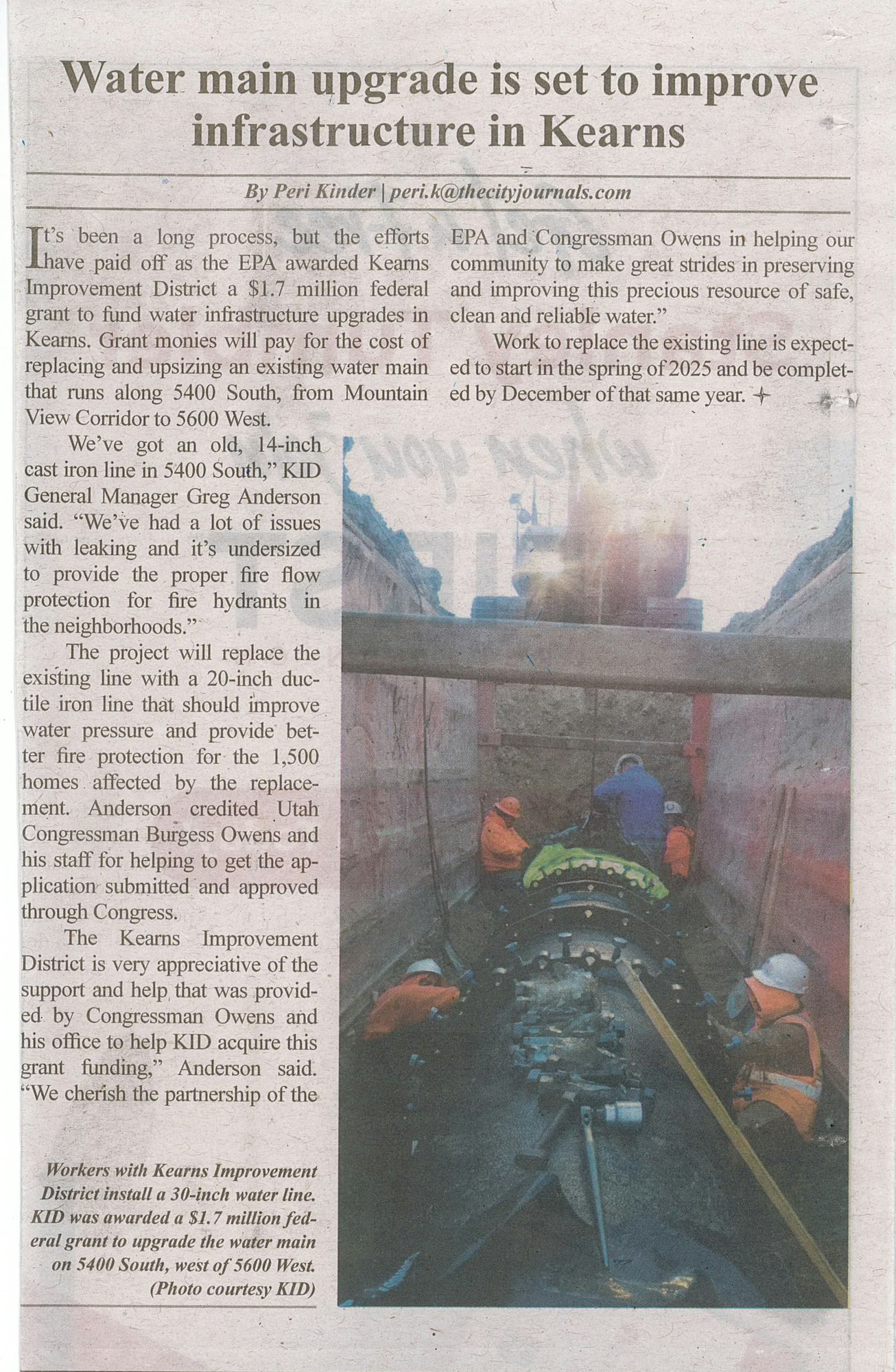 Workers installing a large water pipe in a trench; newspaper article about infrastructure upgrade.