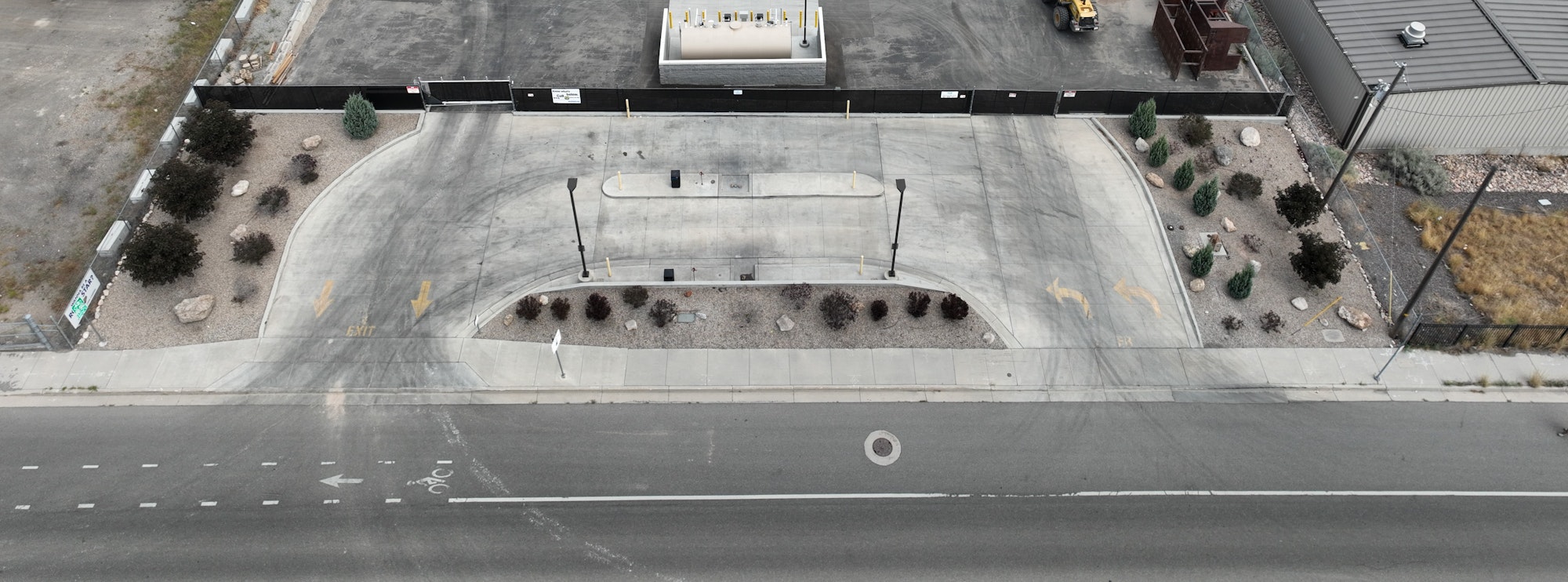Aerial view of a street with a divided entrance to a RV Dump, landscaping, and directional markings.
