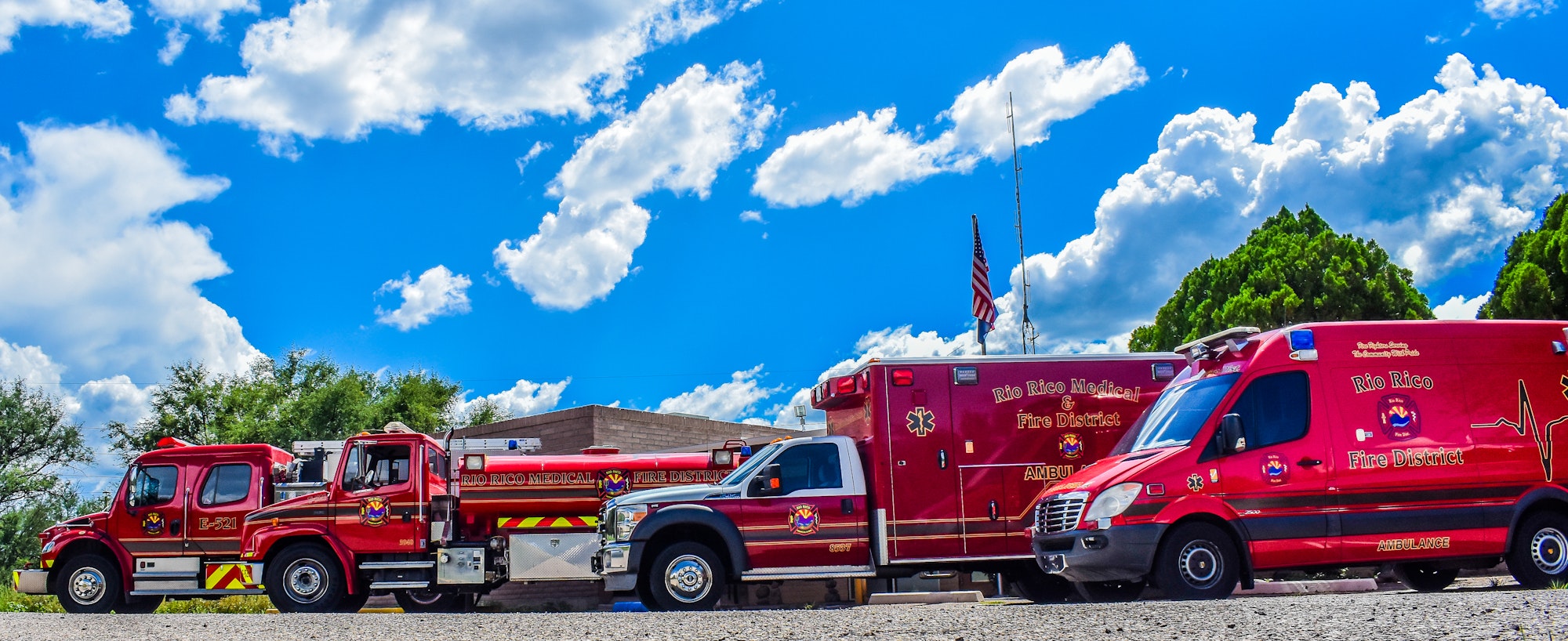 Row of Rio Rico Fire District emergency vehicles under a blue sky.
