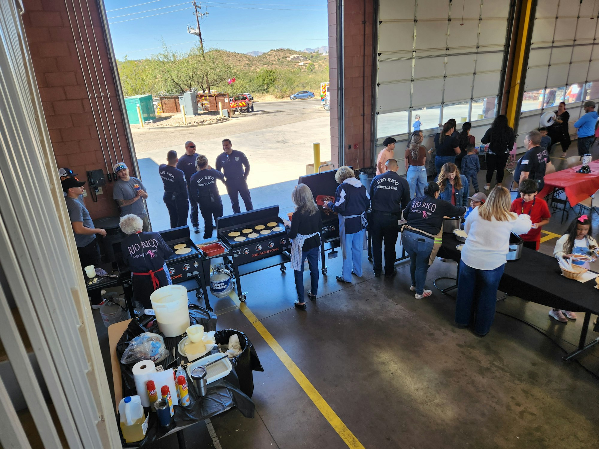 People gathered in a fire station for a community event, cooking pancakes and socializing.