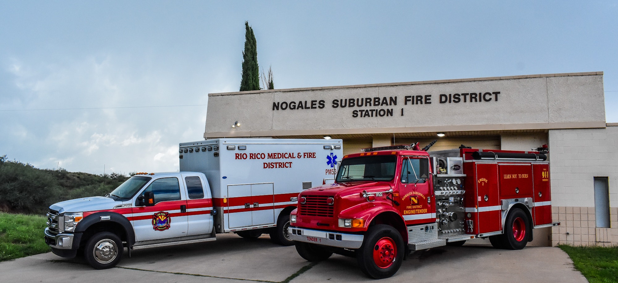 Fire station with a fire truck and emergency vehicle parked outside.