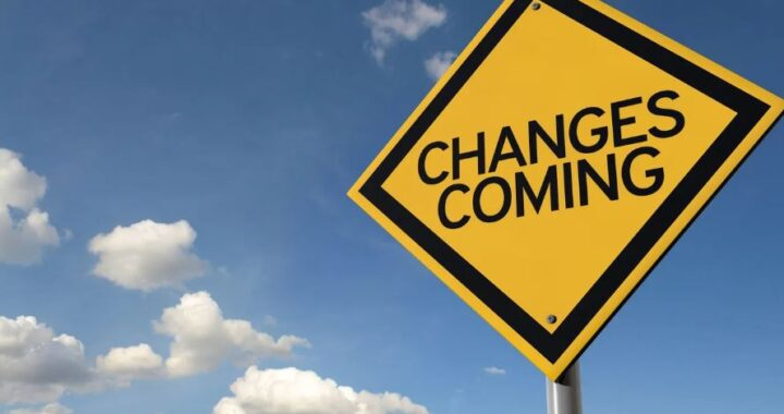 A yellow road sign with "CHANGES COMING" text against a blue sky with clouds.