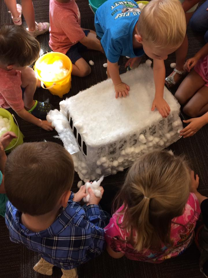Children engaging with a craft activity, creating a faux igloo with cotton balls.
