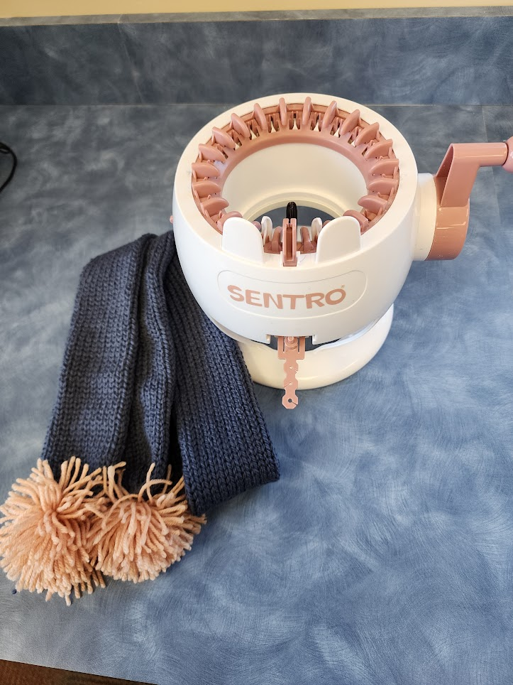 A SENTRO knitting machine with a partially knit scarf.