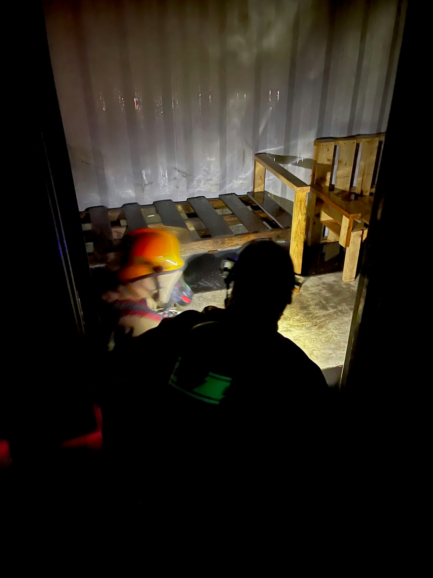 A person with a helmet working in a dark, industrial setting.