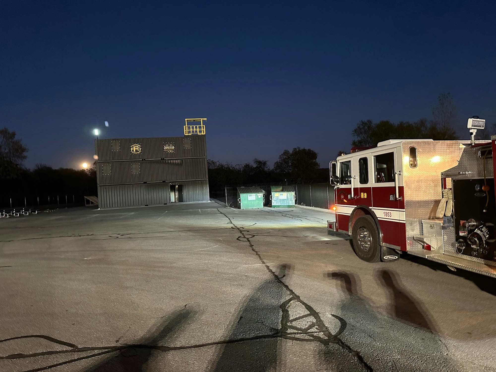 A fire truck parked near a training facility at dusk.