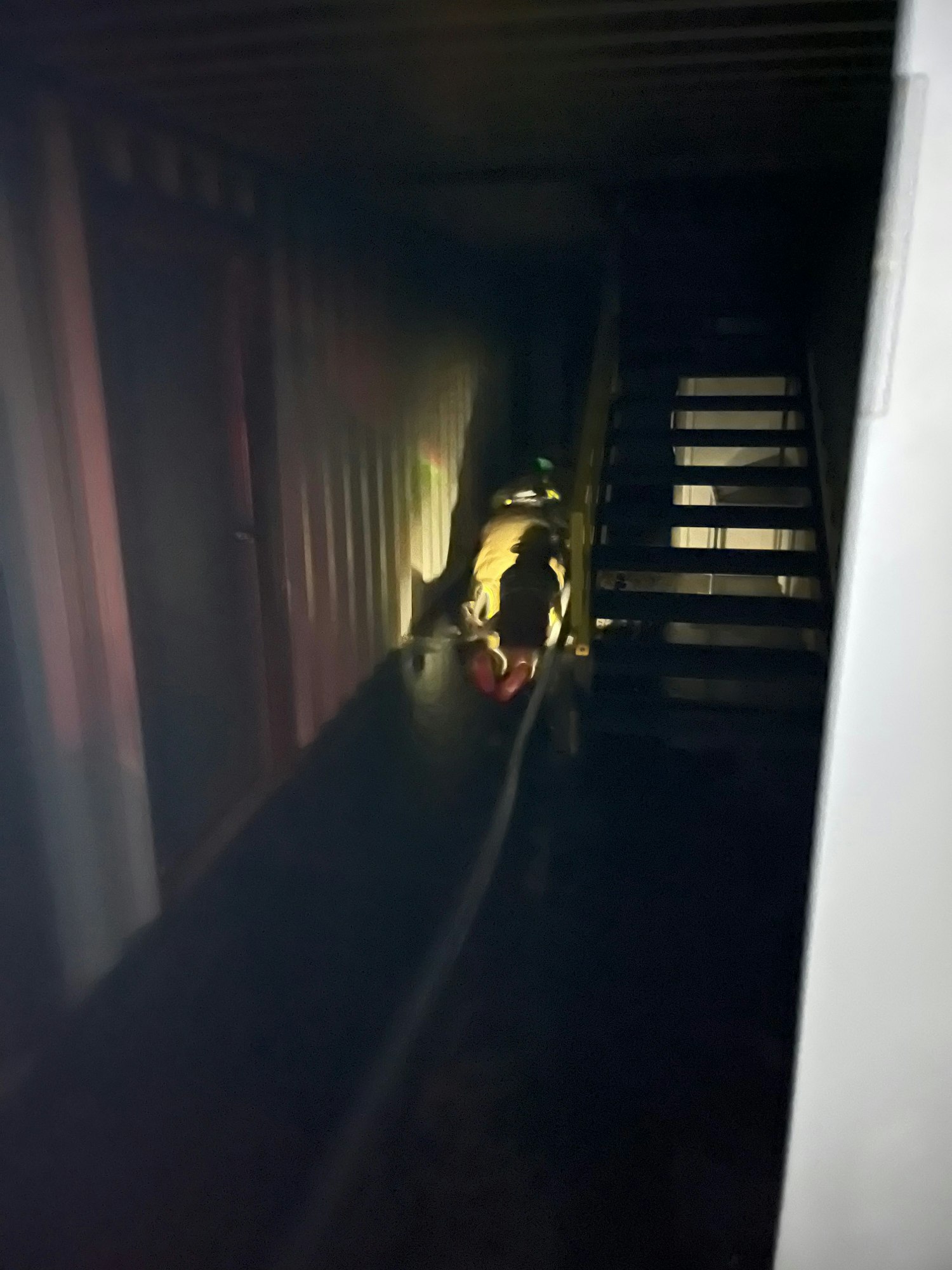 Dark image showing a light beam on stairs, with a blurred figure lying down.