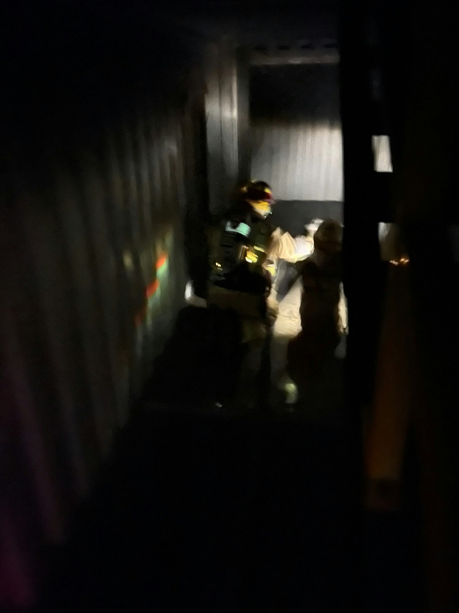 Blurred image of a figure on stairs, low light, possibly in motion or emergency situation.