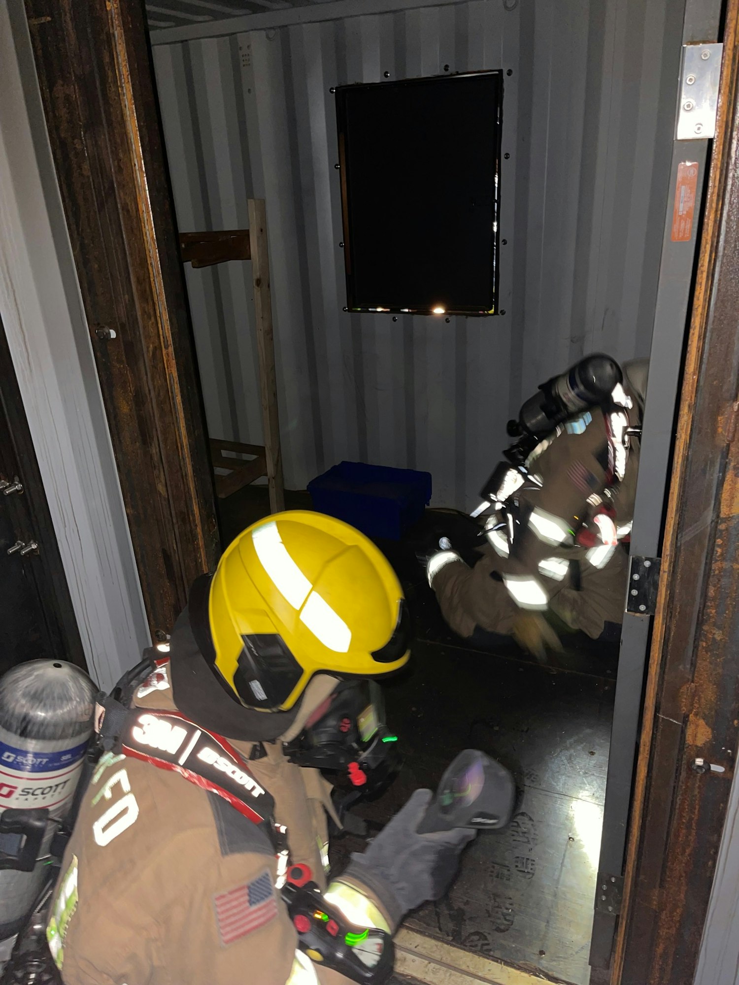 Firefighter in gear training in a dark, simulated environment.