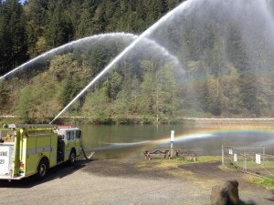 Fire trucks spraying water at Leaburg Lake with rainbows being formed by water mist