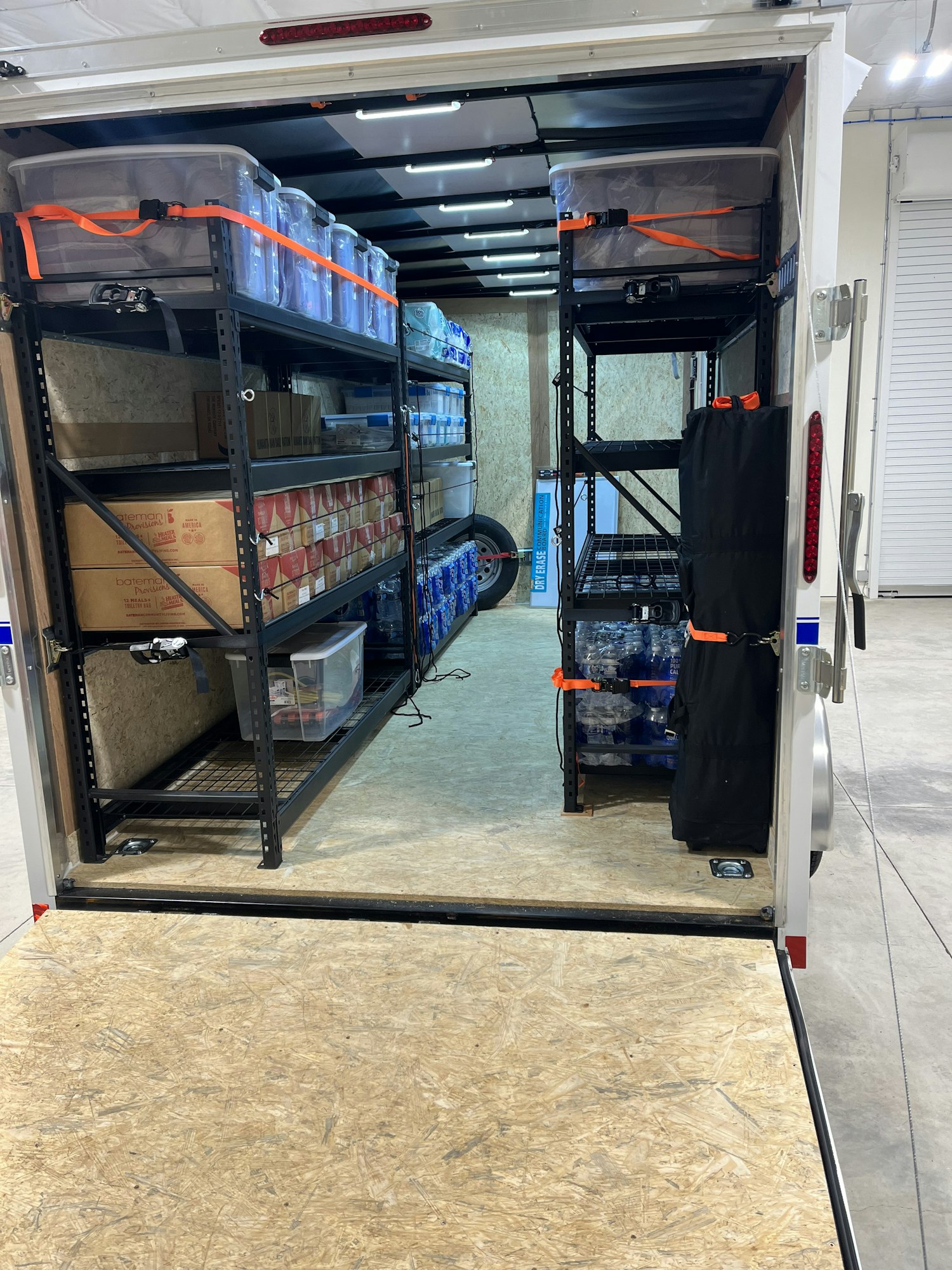 Interior of a delivery van with organized shelves, packed with plastic bins and cardboard boxes. (Image is rotated)