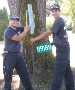 Two personnel installing an address sign