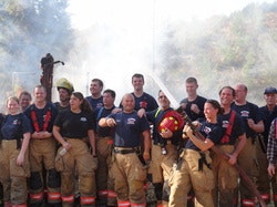 Multiple firefighters in a group in front of burn-to-learn structure