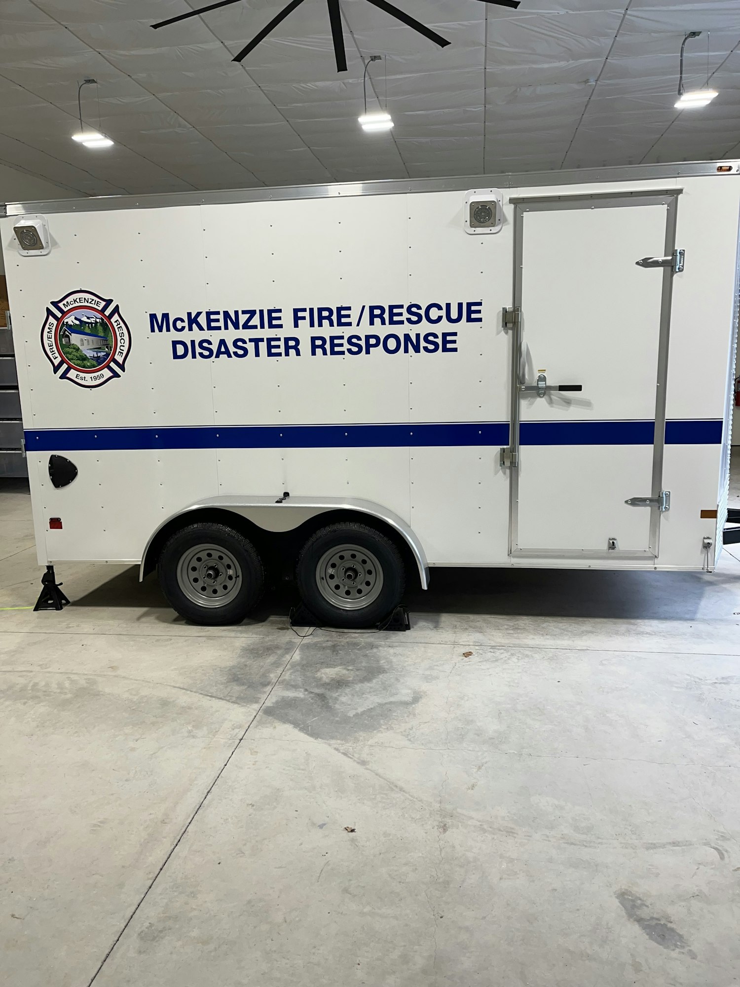 A side view of a disaster response trailer with text "McKenzie Fire Rescue Disaster Response" and the logo. Image is rotated.