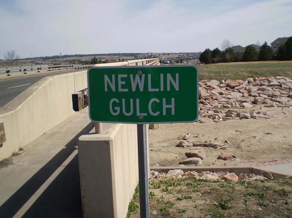 Photo of landscape and a sign for Newlin Gulch