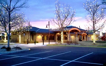 Photo of a parking lot, front of a building, and lighted trees