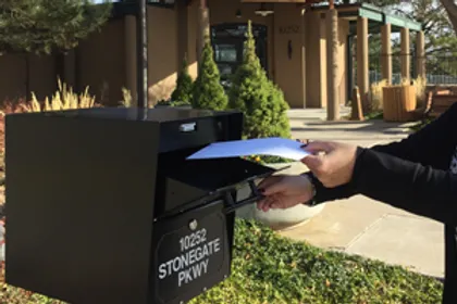 Photo of a person putting a letter in a post box