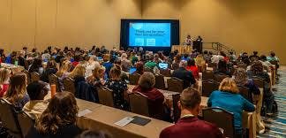 A conference room with attendees facing a presentation screen displaying a "Thank you" message.