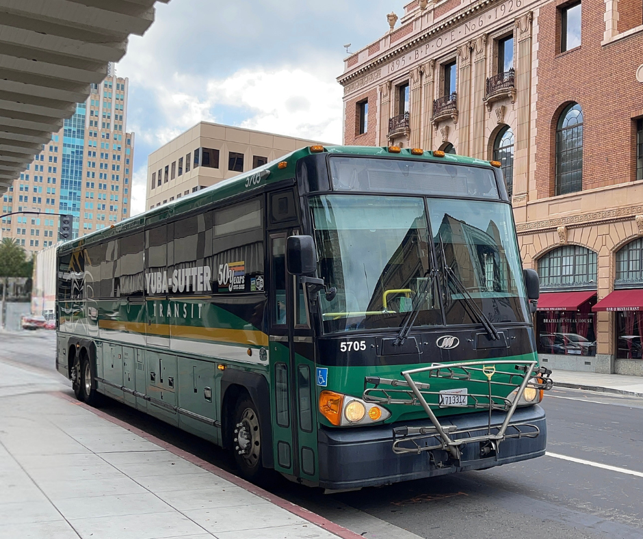The image shows a Yuba-Sutter Transit bus parked on a street, with nearby buildings in a city setting.