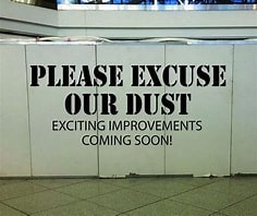 A sign reads "PLEASE EXCUSE OUR DUST EXCITING IMPROVEMENTS COMING SOON!" likely signaling construction or an update ahead.