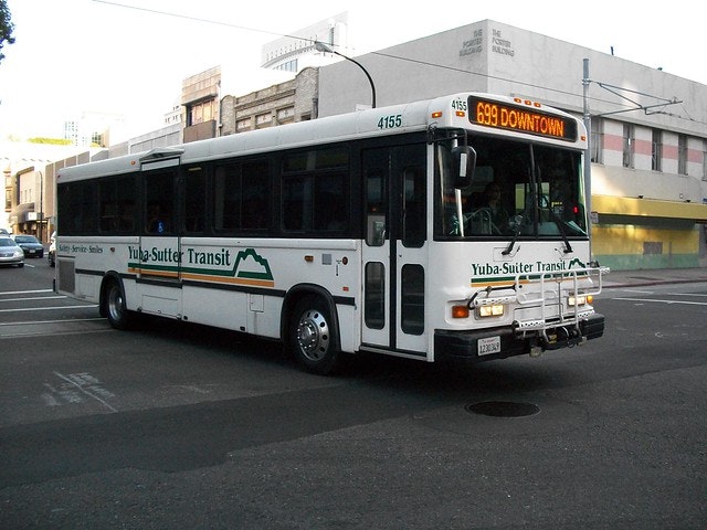 A Yuba-Sutter Transit bus on route 699 to downtown, driving on an urban street.