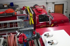 A red fire truck with equipment parked inside a garage.
