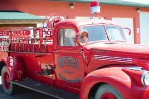 A vintage red fire truck with "Wilson Valley Fire District" written on the side, parked in front of a building.