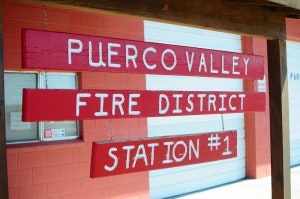 Sign for "Puerco Valley Fire District Station #1" in front of a building.