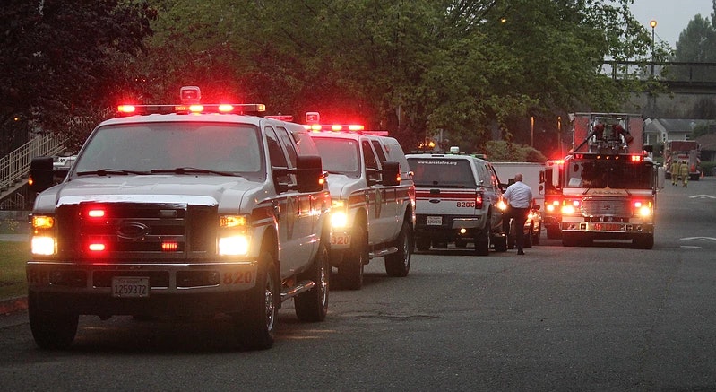 Group of utilities and a ladder truck at an incident.